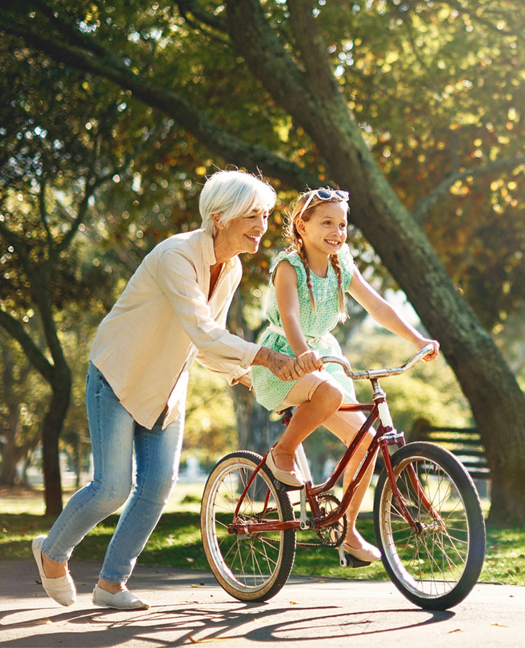 Grandmother helping granddaughter ride a bicycle