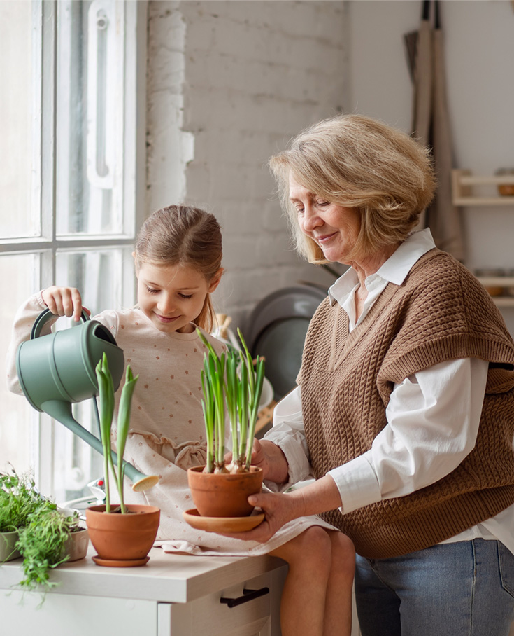 Grandmother helping granddaughter with potting tulip bulbs