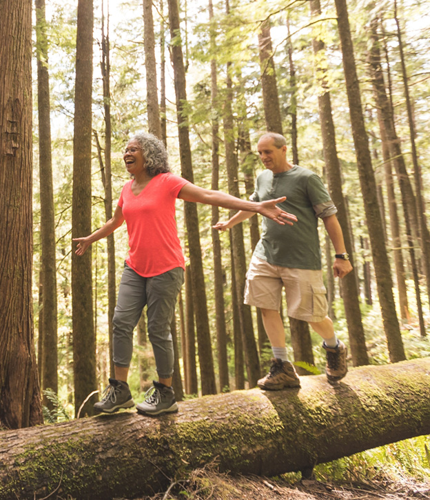couple hiking and walking along a fallen log