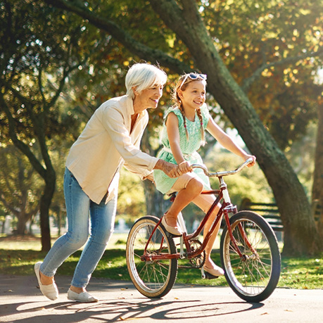 Grandmother helping granddaughter ride a bicycle